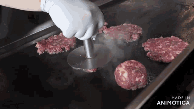 a hamburger patty is being cooked on a grill with the words made in animotica below it