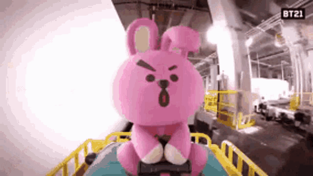 a pink stuffed animal is riding a roller coaster in a parking garage .