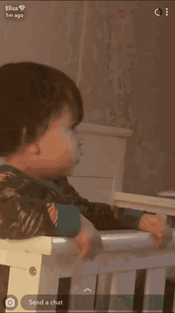 a baby is sitting in a crib with the words send a chat on the bottom right