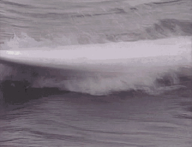 a black and white photo of a surfboard in the water