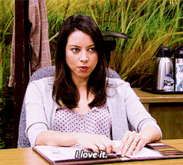 a woman sits at a desk with a menu open and says i love it