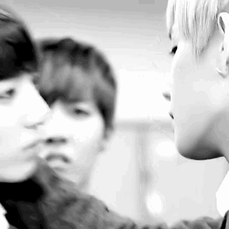 a black and white photo of two young men kissing each other in a room .