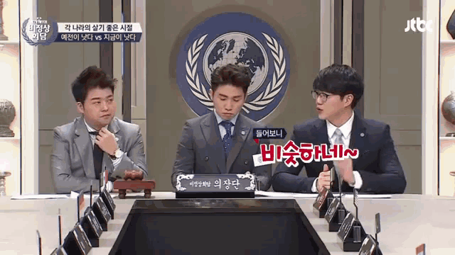 a group of men are sitting around a table with a sign that says ' jtb ' on it
