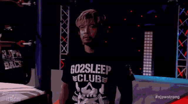 a man in a go2sleep club shirt stands in a ring