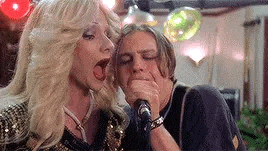 a man and a woman are singing into a microphone in a bar .