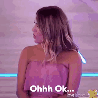 a woman in a purple dress is sitting on a couch and says `` ohh ok '' .