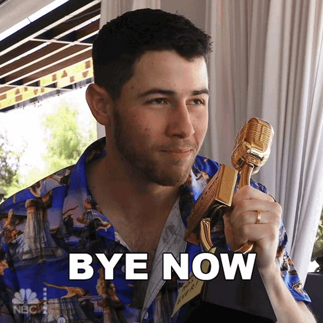 a man in a blue shirt is holding a microphone and the word bye now is on the bottom