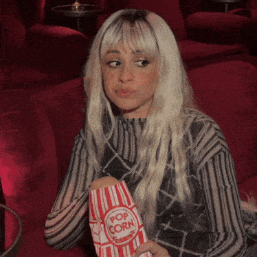 a woman holding a bag of pop corn in a movie theater