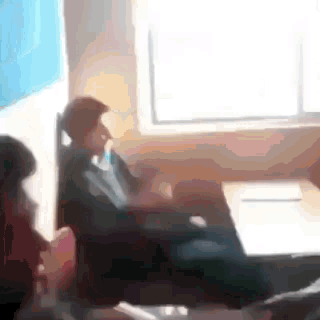 a blurry picture of a man sitting at a table in a room .