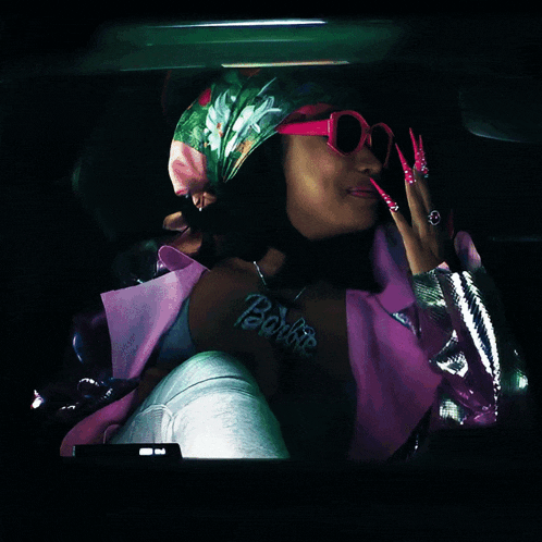 a woman wearing sunglasses and a necklace with the word barbie on it