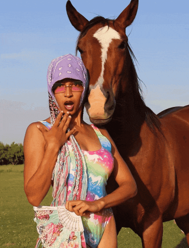 a woman standing next to a brown horse holding a fan
