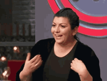 a woman wearing a black shirt and a black cardigan stands in front of a red circle