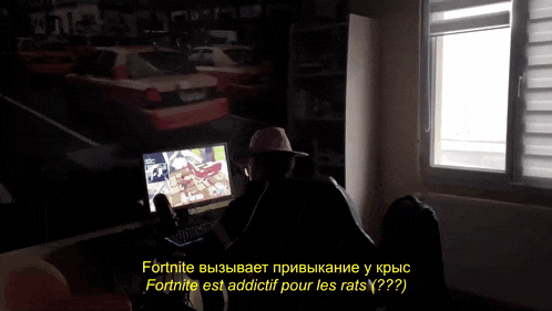 a man in a hat sits in front of a computer screen with the words fortnite on the bottom right