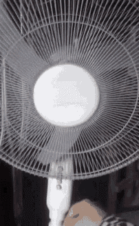 a person is holding a white fan with a light on it