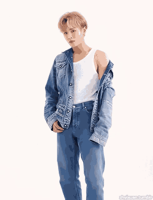 a man wearing a white tank top and a denim jacket