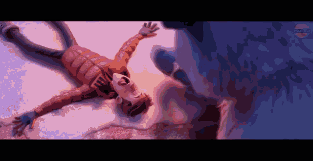 a boy in a red jacket is laying on the ground in the snow
