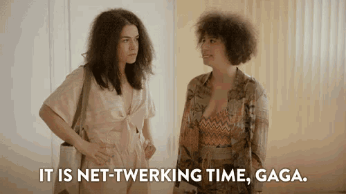 two women are standing next to each other in a room talking to each other .