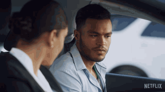 a man and a woman are sitting in a car with netflix written on the bottom of the screen