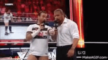 two wrestlers are talking into microphones in a ring .