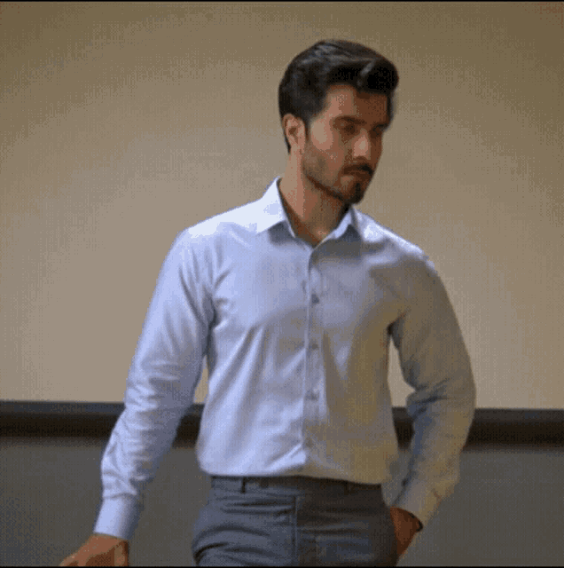 a man wearing a light blue dress shirt and grey pants