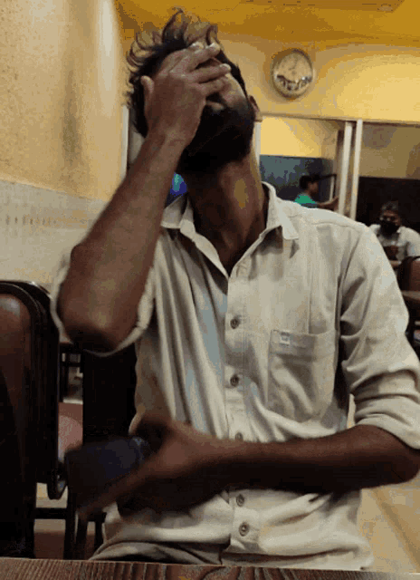 a man sitting at a table with his hand on his face
