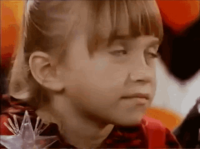 a close up of a young girl 's face with a star on her shoulder .