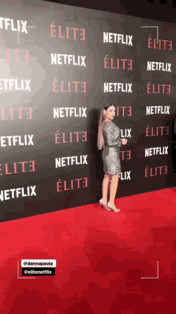 a woman stands in front of a wall that says netflix elite