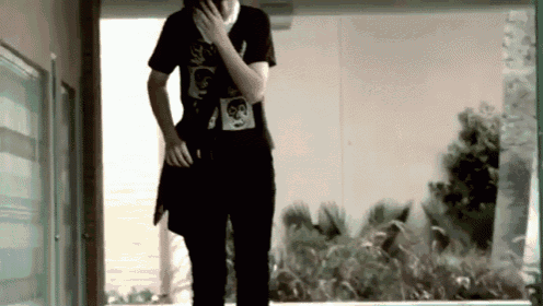 a man wearing a black shirt with a skull on it is talking on a cell phone