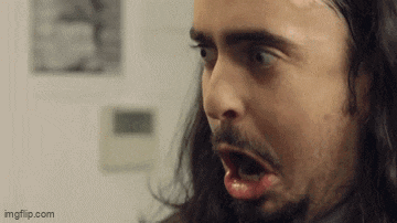 a man with a beard and long hair is making a funny face .