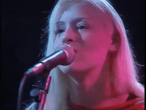 a woman is singing into a microphone on stage .