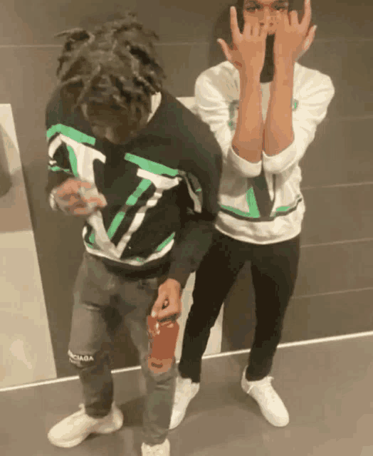 a man wearing a green and white shirt with the letter v on it stands next to another man