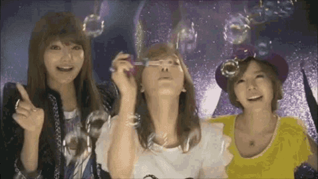 three women are blowing soap bubbles in front of a starry sky .