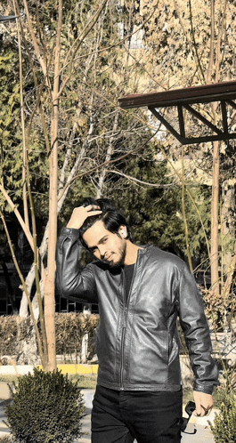 a man in a leather jacket holds a pair of sunglasses in his hand