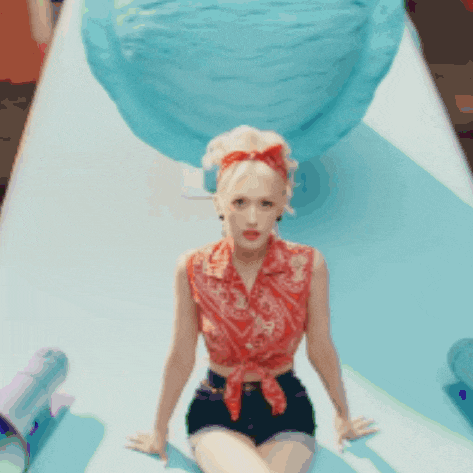 a woman in a red top and black shorts sits on a slide