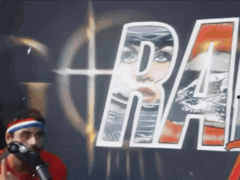a man is standing in front of a microphone in front of a sign that says ' ral ' on it .