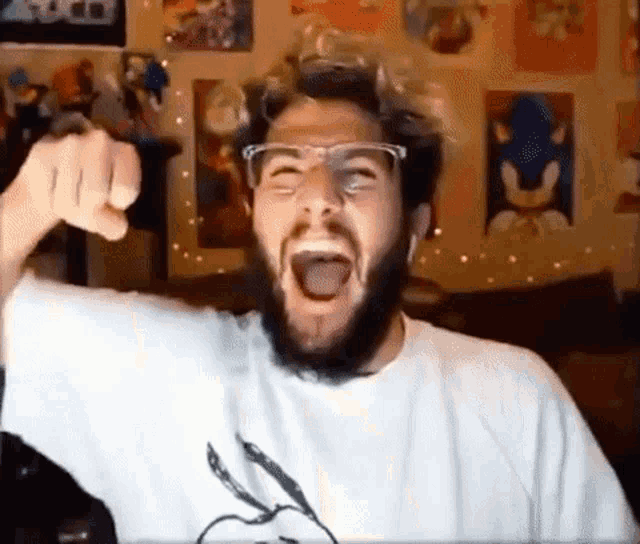 a man with a beard and glasses is screaming in front of a wall with pictures of sonic the hedgehog on it