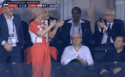 a group of people are watching a soccer game and one of them is clapping .