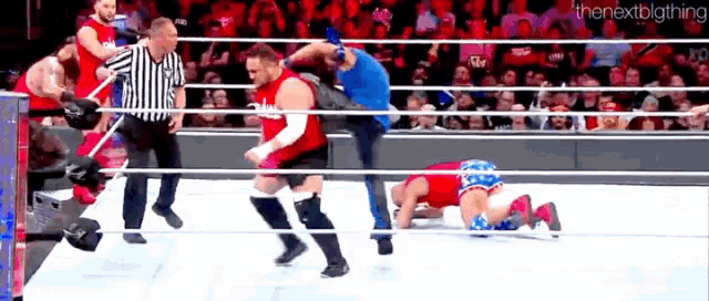 a group of wrestlers are wrestling in a ring with a referee .