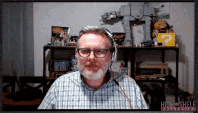 a man wearing headphones is sitting in front of a screen that says high shelf multimedia