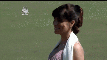 a woman in a pink top is standing in a field with a sign above her that says " estrela "