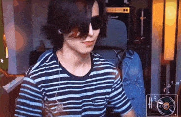 a man wearing sunglasses and a striped shirt is sitting in front of a piano ..