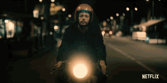 a man in a red helmet is riding a motorcycle down a street with netflix written on the bottom