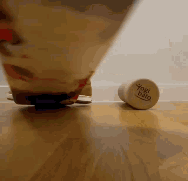 a person is standing on a wooden floor next to a yogi bato bottle