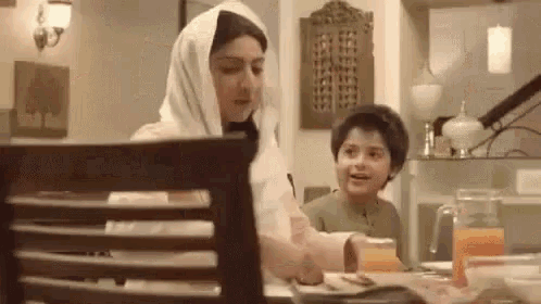 a woman and a child are sitting at a table in a room .