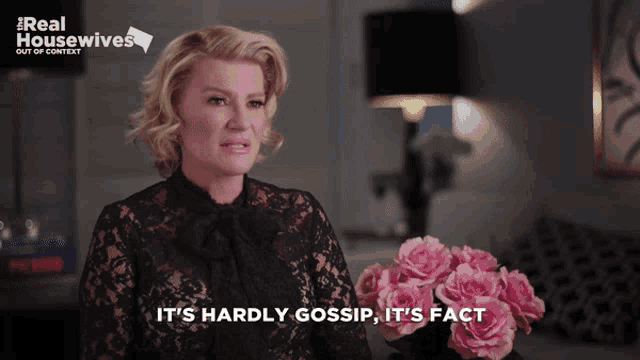 a woman says it 's hardly gossip it 's fact while holding a vase of pink roses