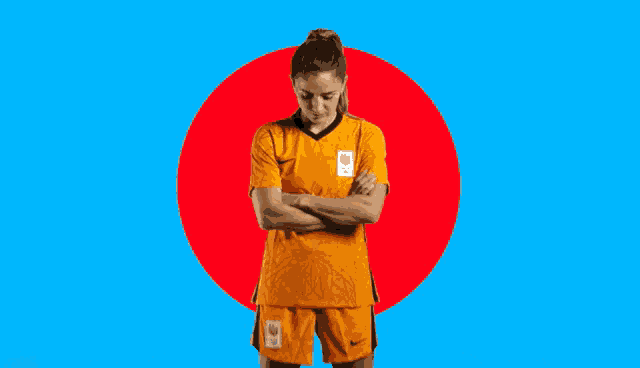 a female soccer player with her arms crossed stands in front of a red circle