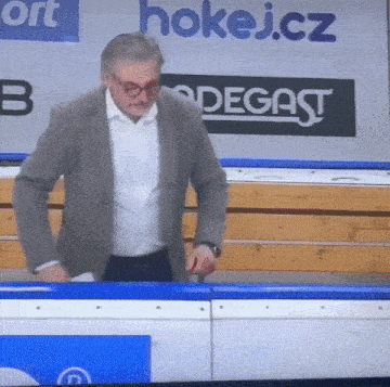a man in a suit is standing in front of a sign that says hokej.cz