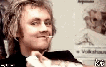a young man with a cigarette in his mouth is smiling .