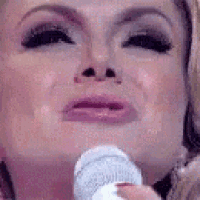 a woman is holding a microphone in front of her face and crying .