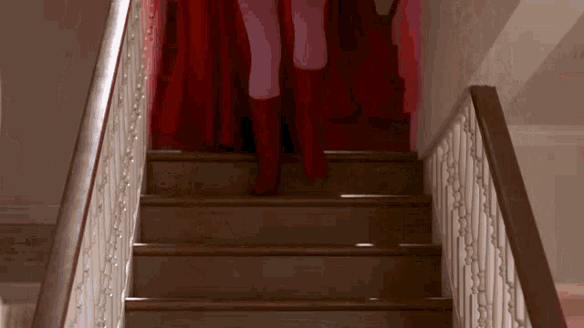 a woman in pink tights and red boots is walking down a set of stairs